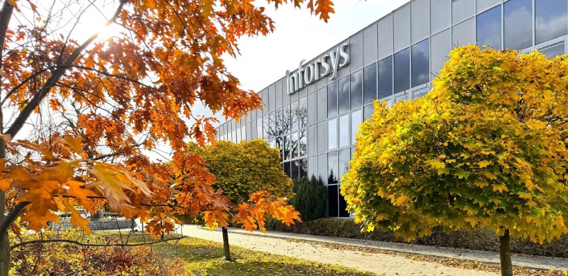 Inforsys office building surrounded by autumn trees with orange and yellow leaves on a sunny day.